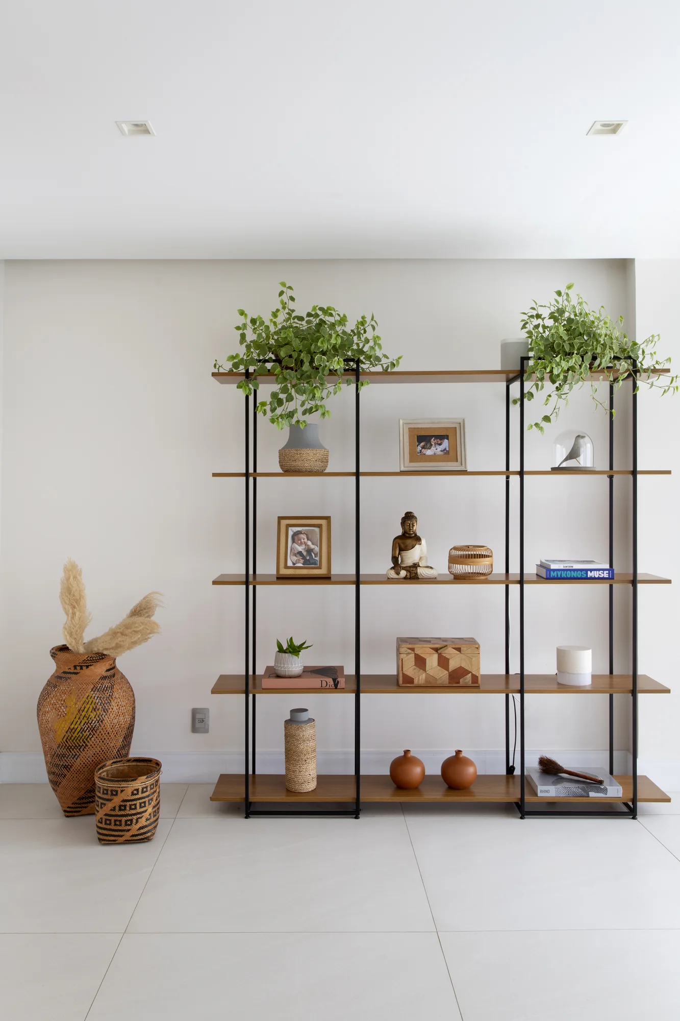 Estante metálica vazada com vasos, plantas e objetos de fibra natural