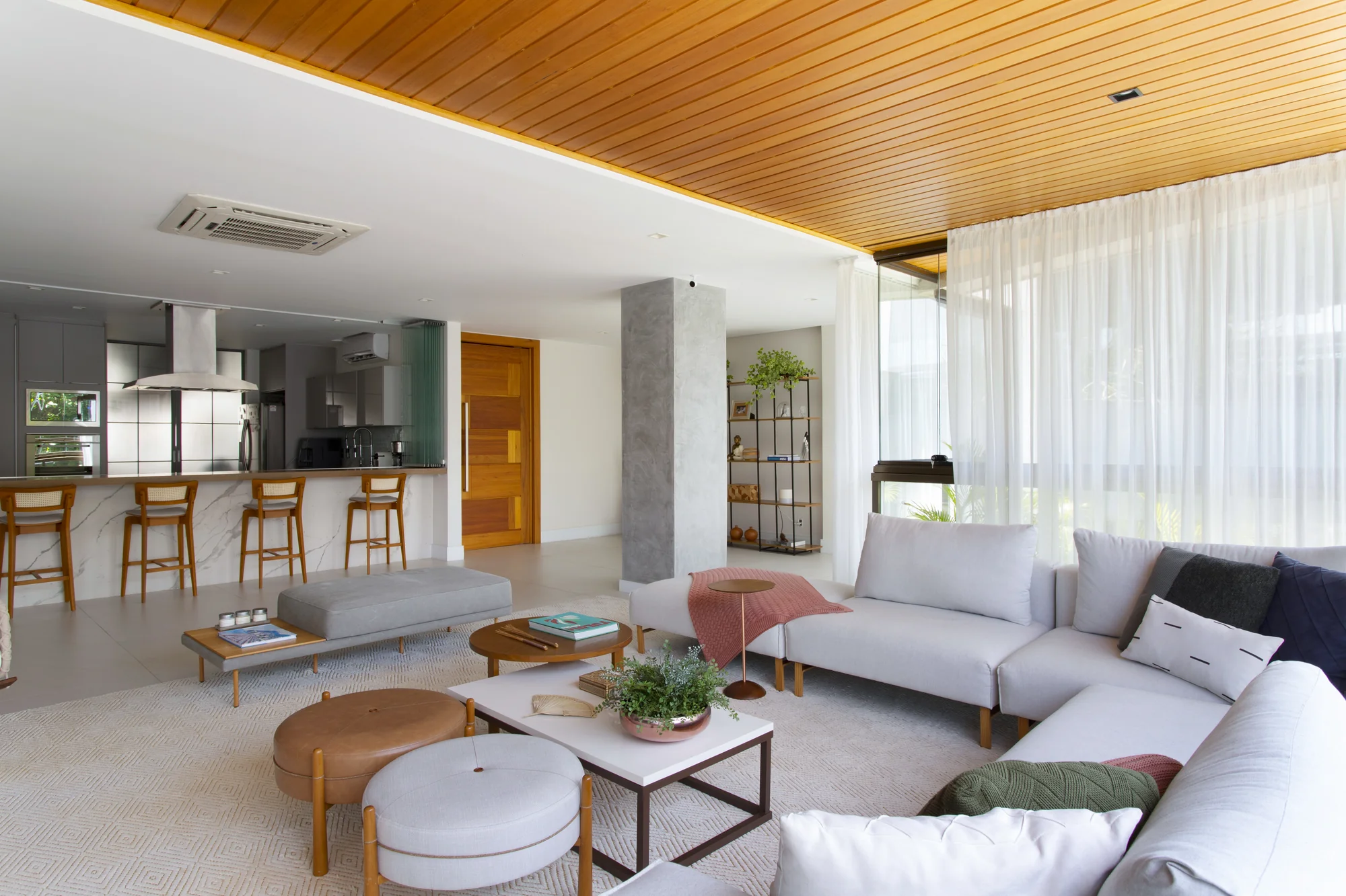 Living e cozinha na mesma perspectiva, com pufes e mesas de centro em primeiro plano
