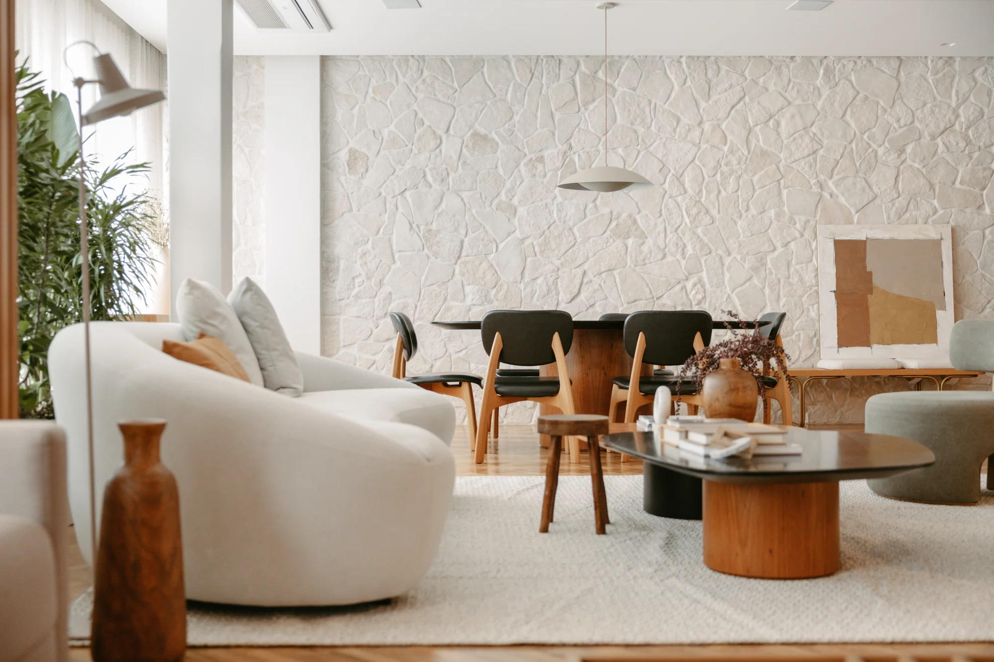 Living e jantar integrados, com sofá curvo branco e tapete claro