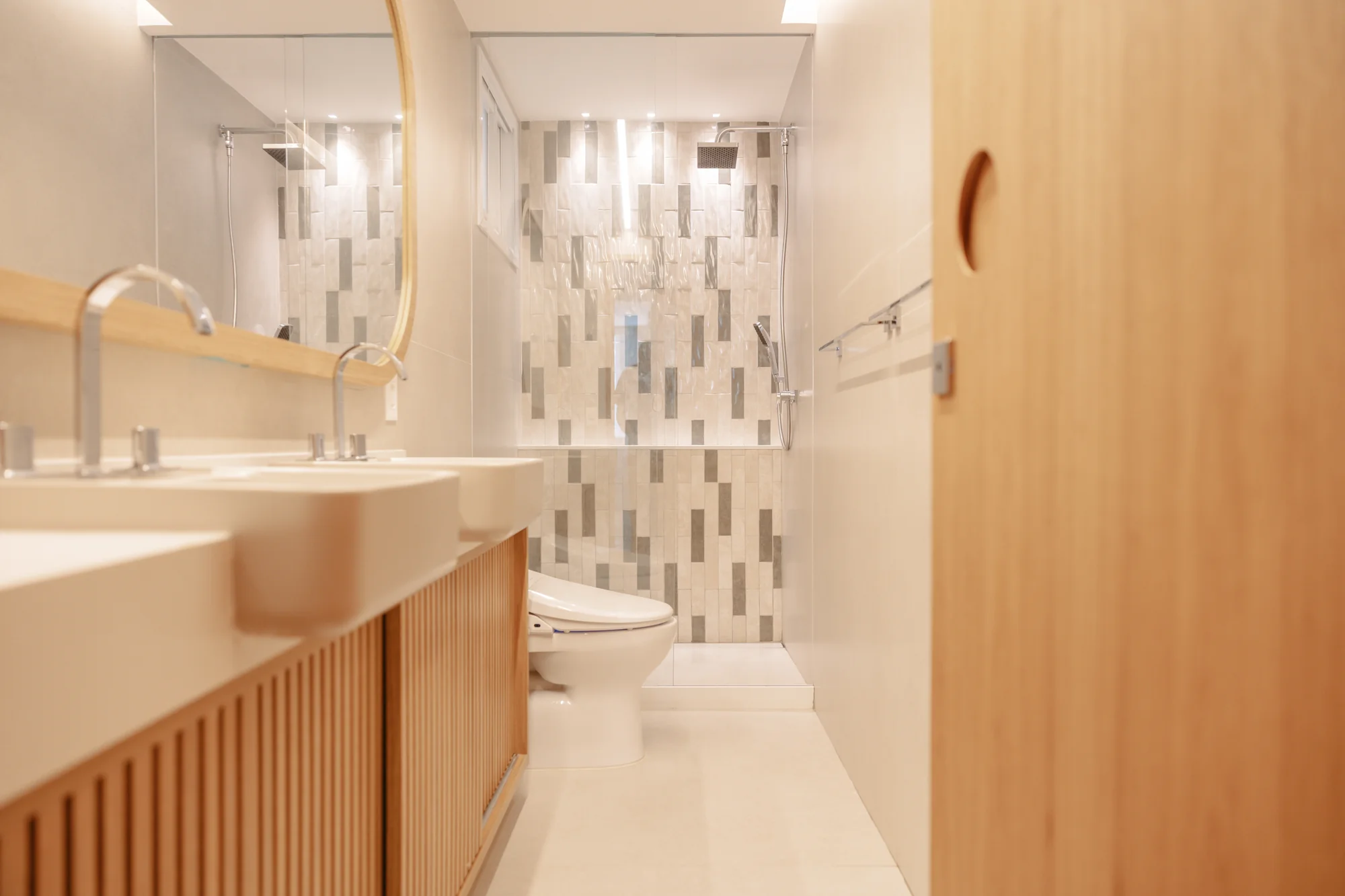Lavabo com marcenaria ripada, espelho oval e pastilhas verticais