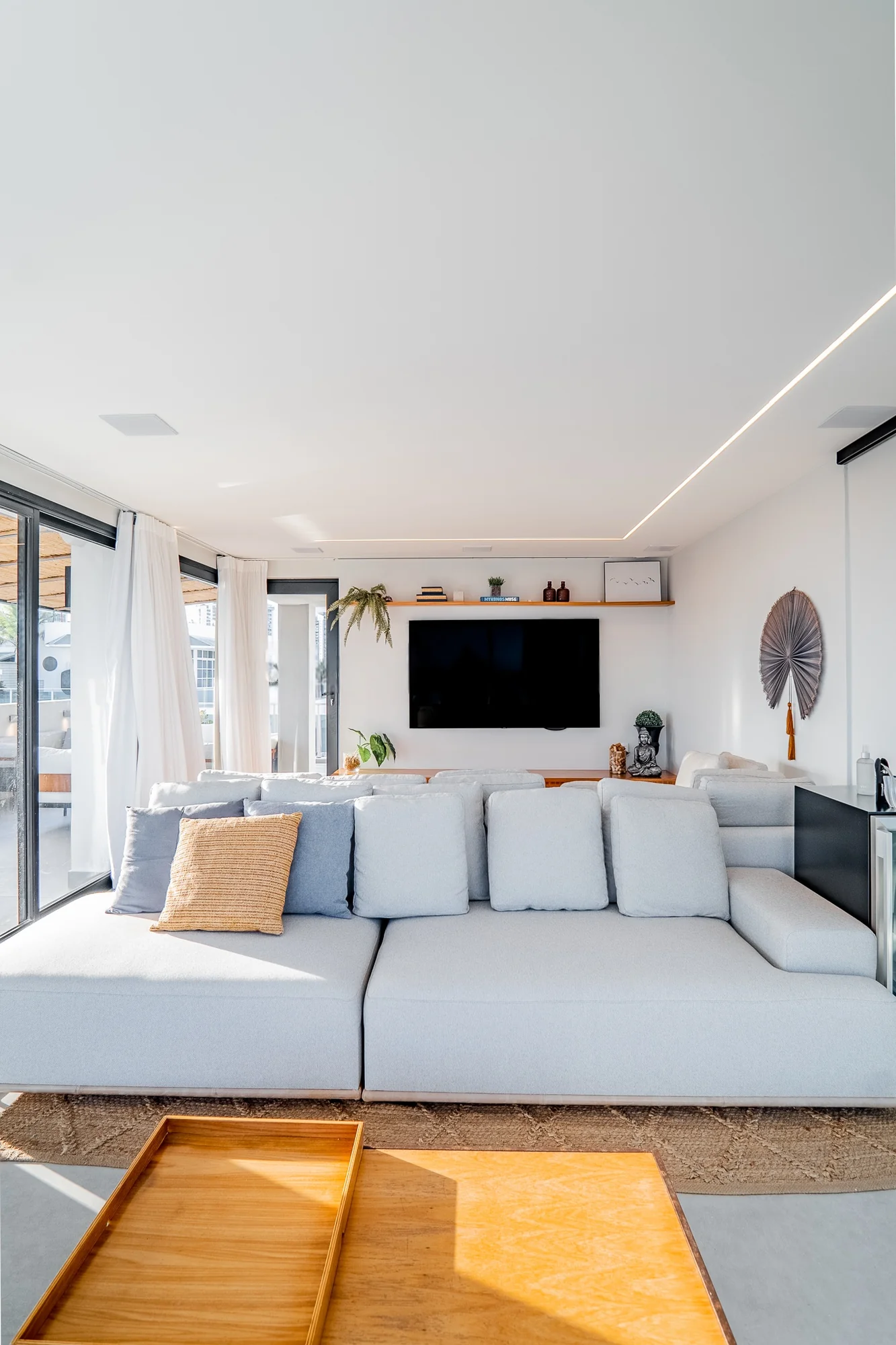 Living com sofá modular claro, tapete de fibra e varanda ao fundo