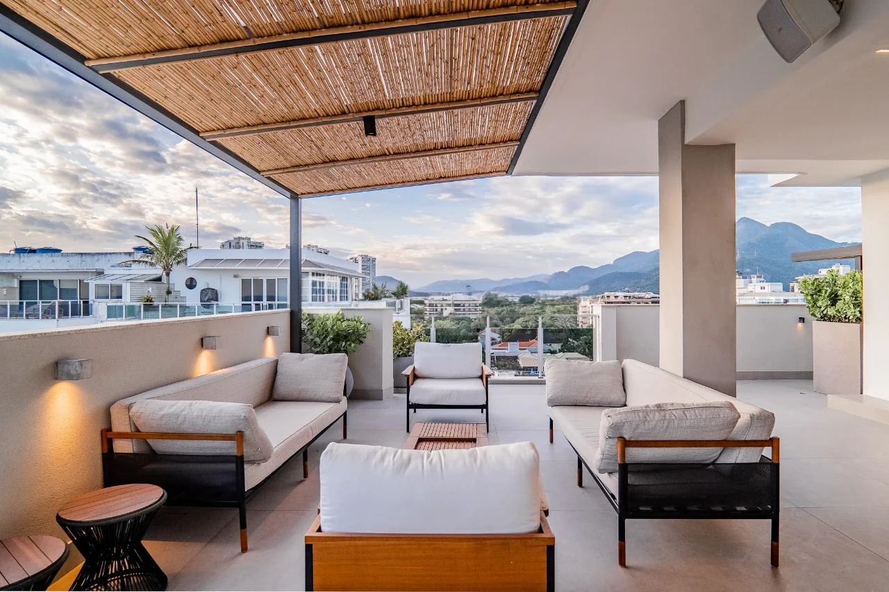 Terraço com forro de bambu, sofás baixos e vista para os morros