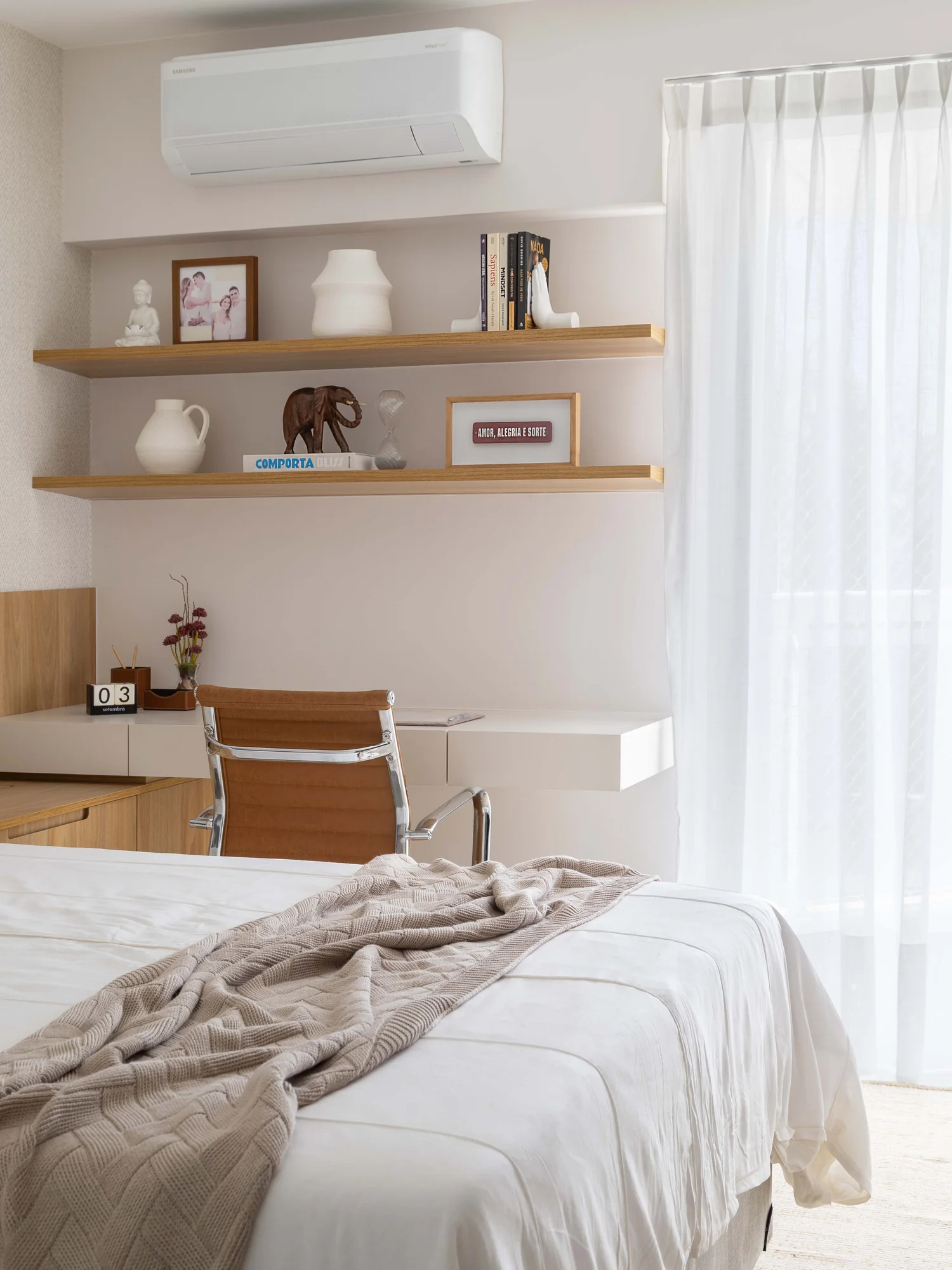 Quarto de casal com nichos de madeira, escrivaninha junto à janela e cortina de voil