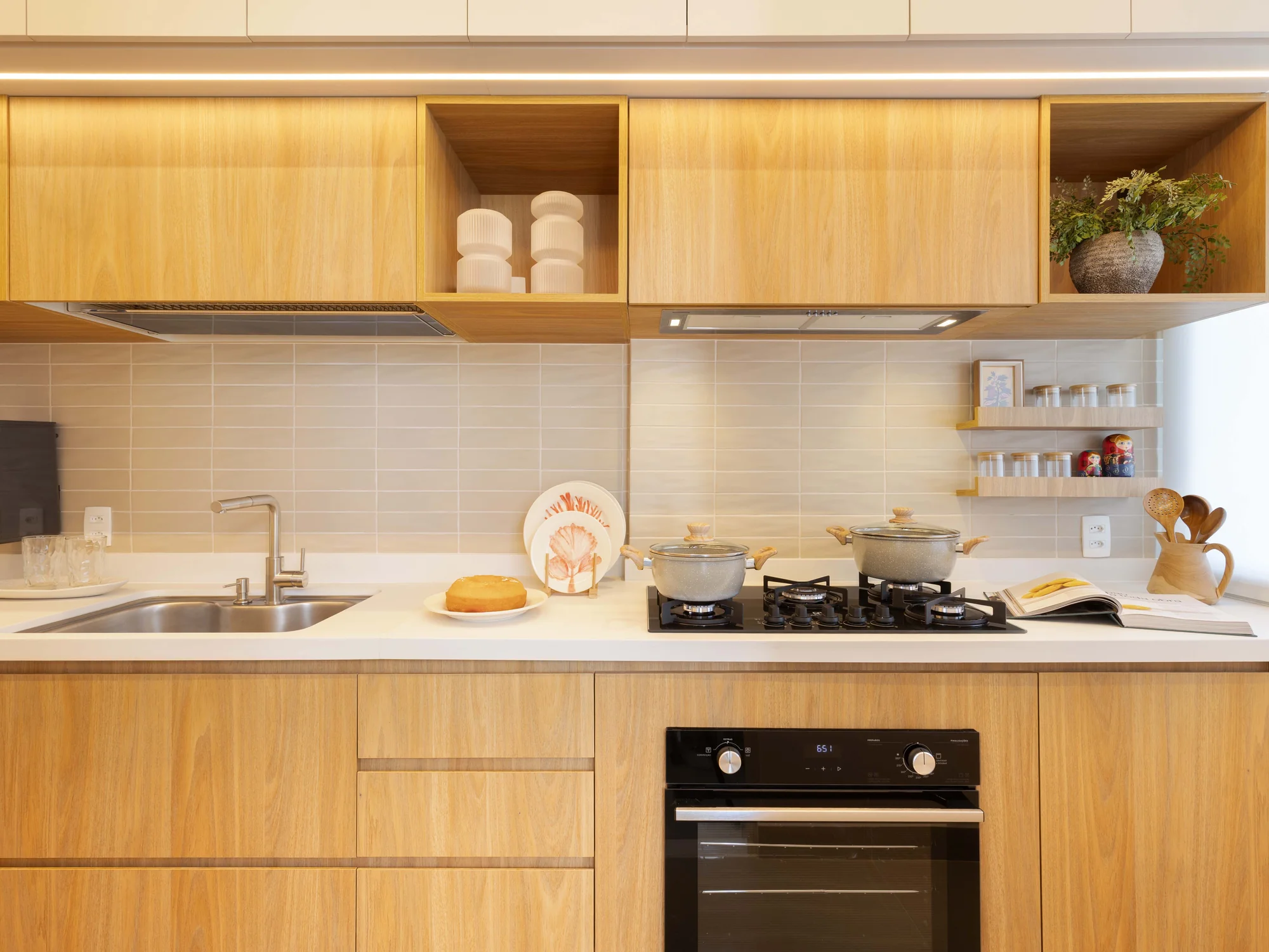 Cozinha em marcenaria clara com cuba, cooktop e forno embutido