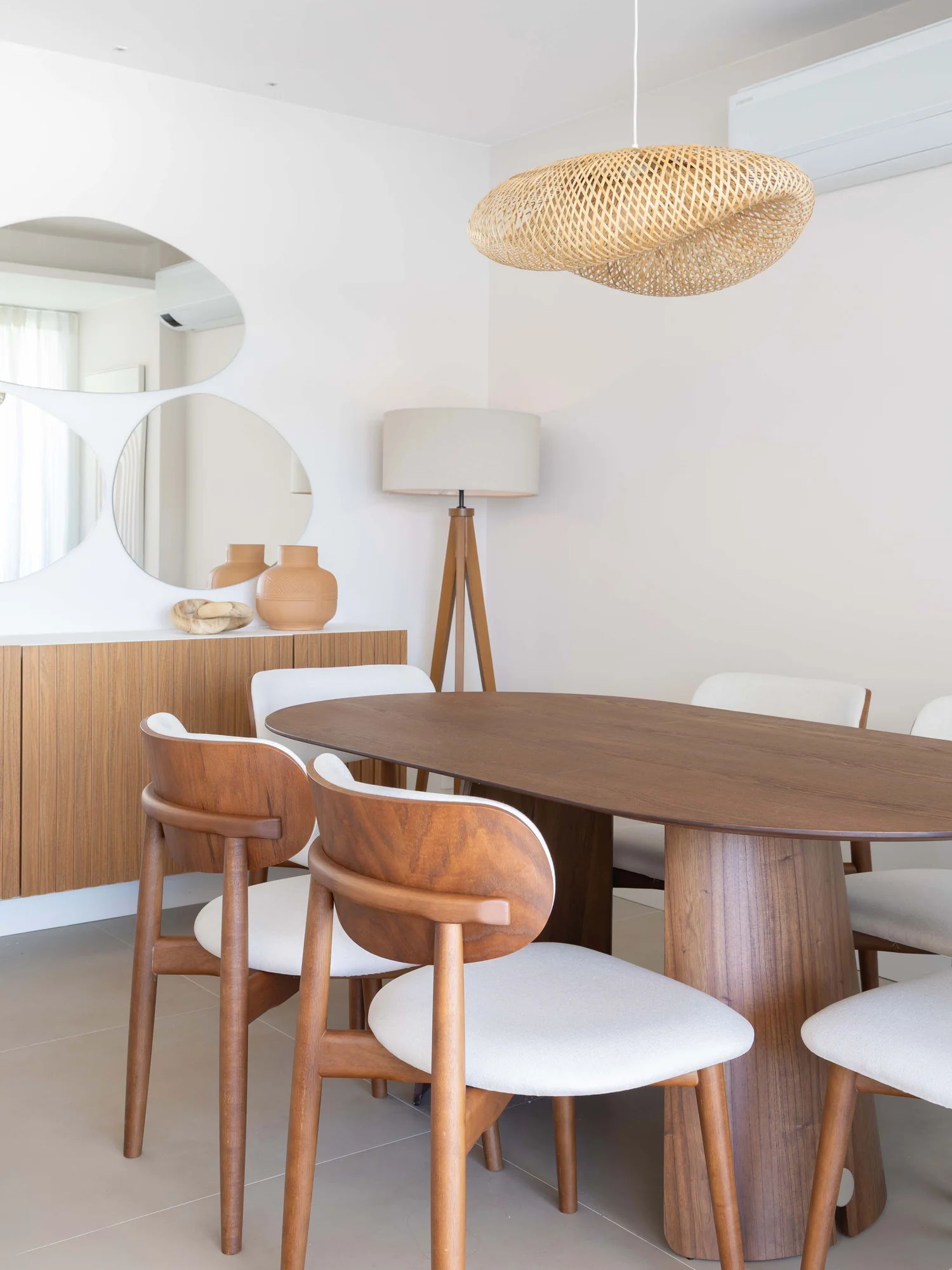 Mesa de jantar oval de madeira com cadeiras estofadas e pendente de fibra