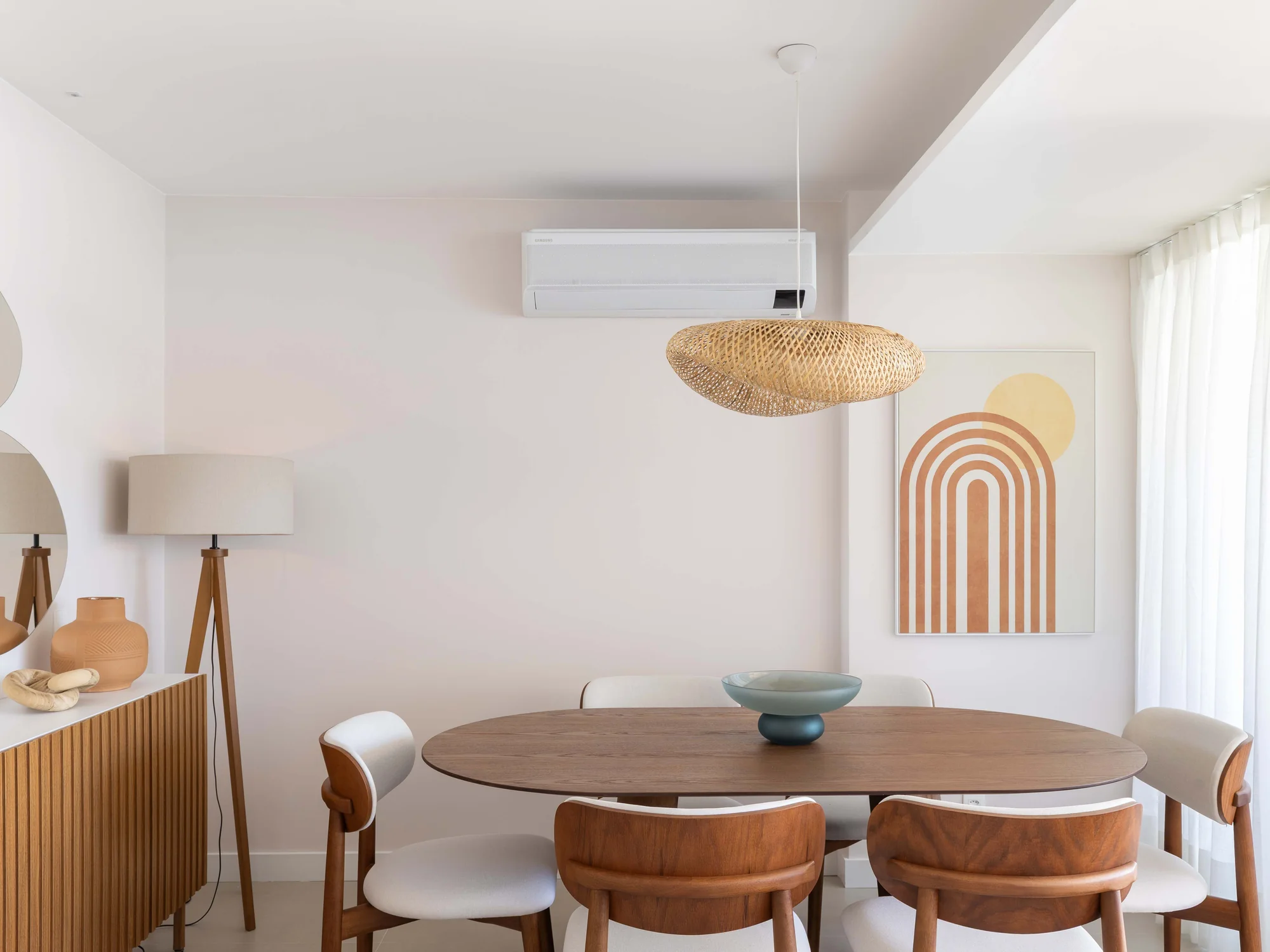 Sala de jantar com painel ripado, luminária de piso e quadro geométrico