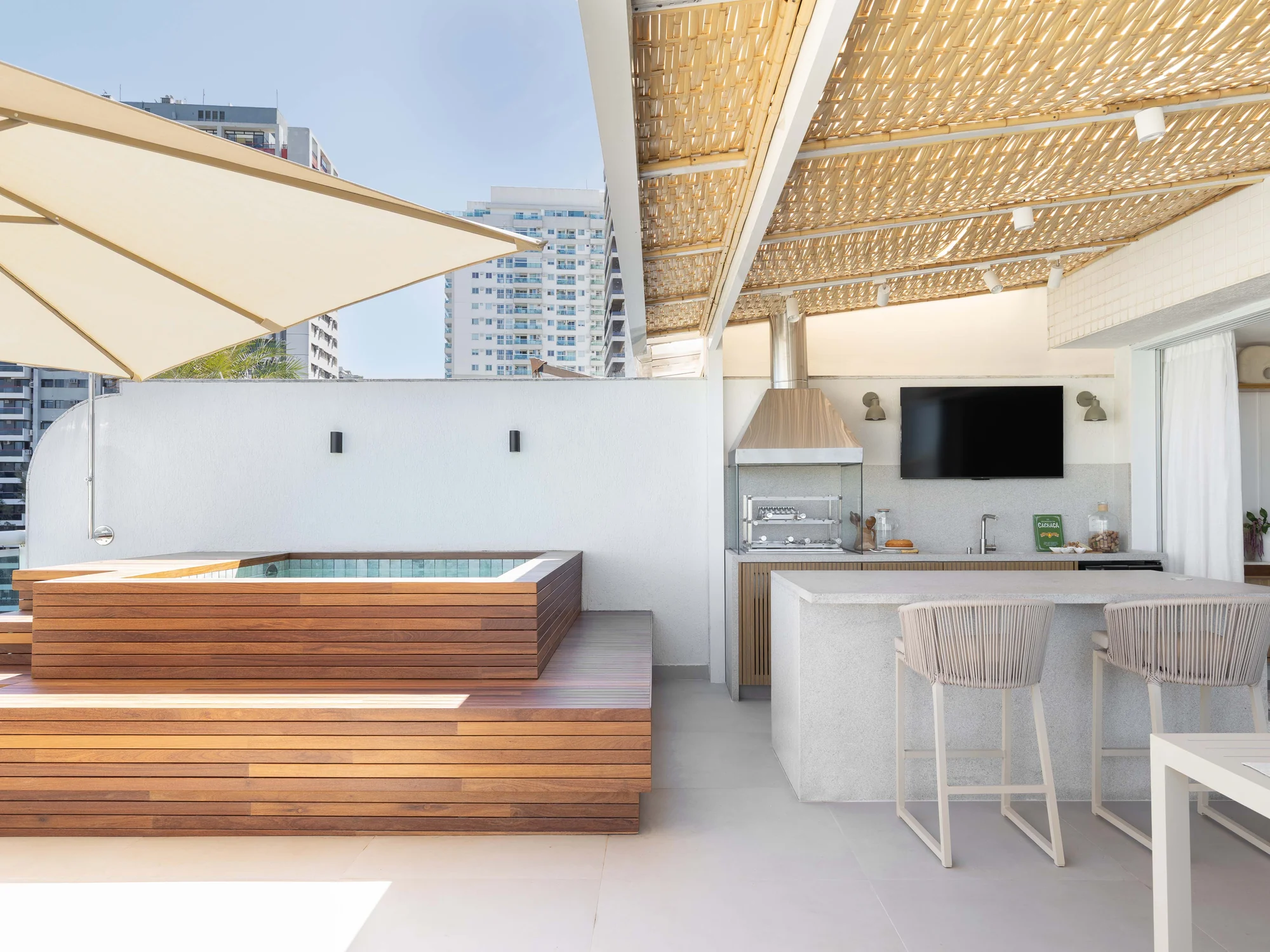 Varanda gourmet com pergolado de palha, deck de madeira com piscina embutida, churrasqueira e bancada com banquetas de fibra