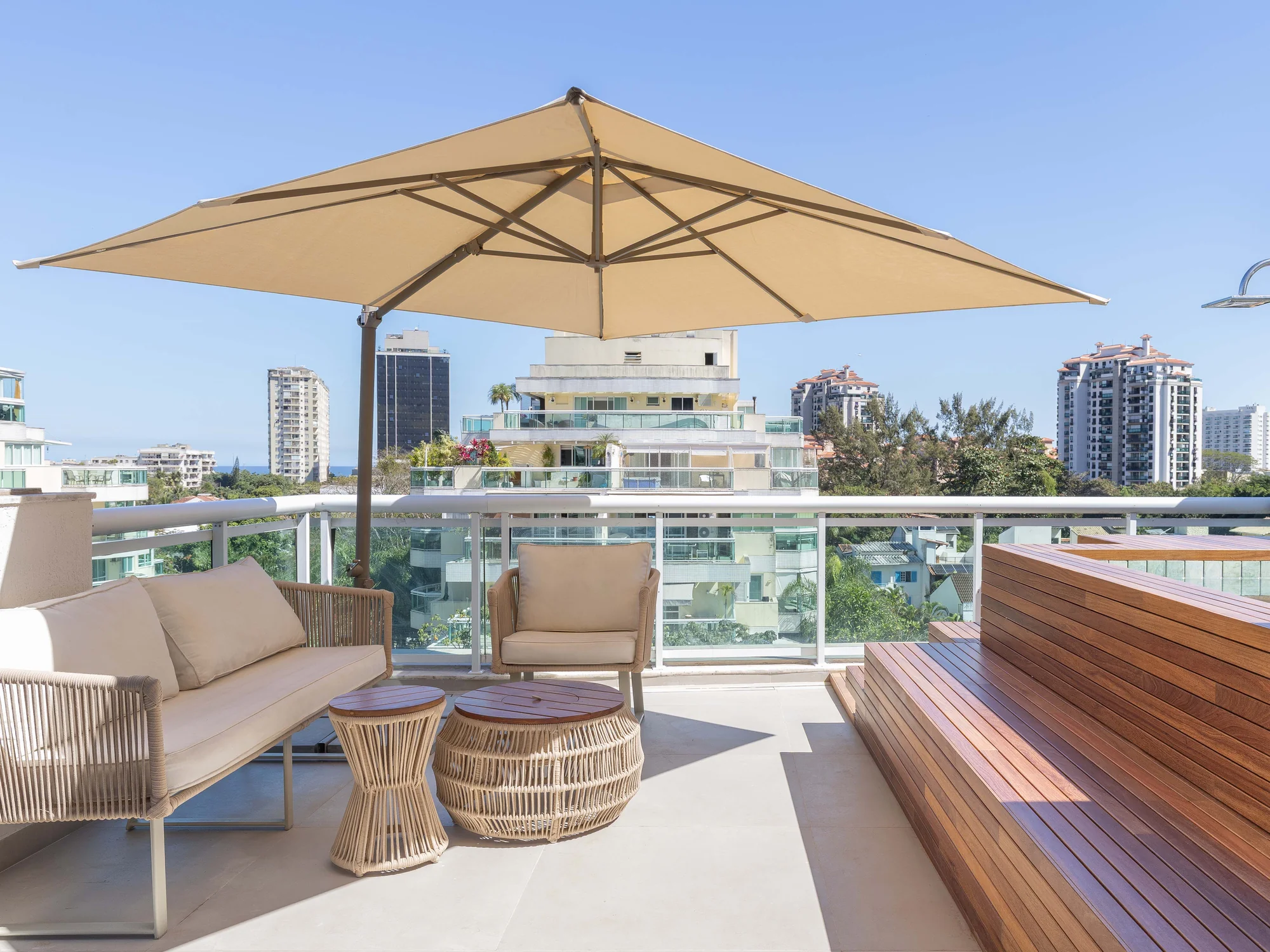 Terraço com sofá de fibra, ombrelone e vista para a cidade