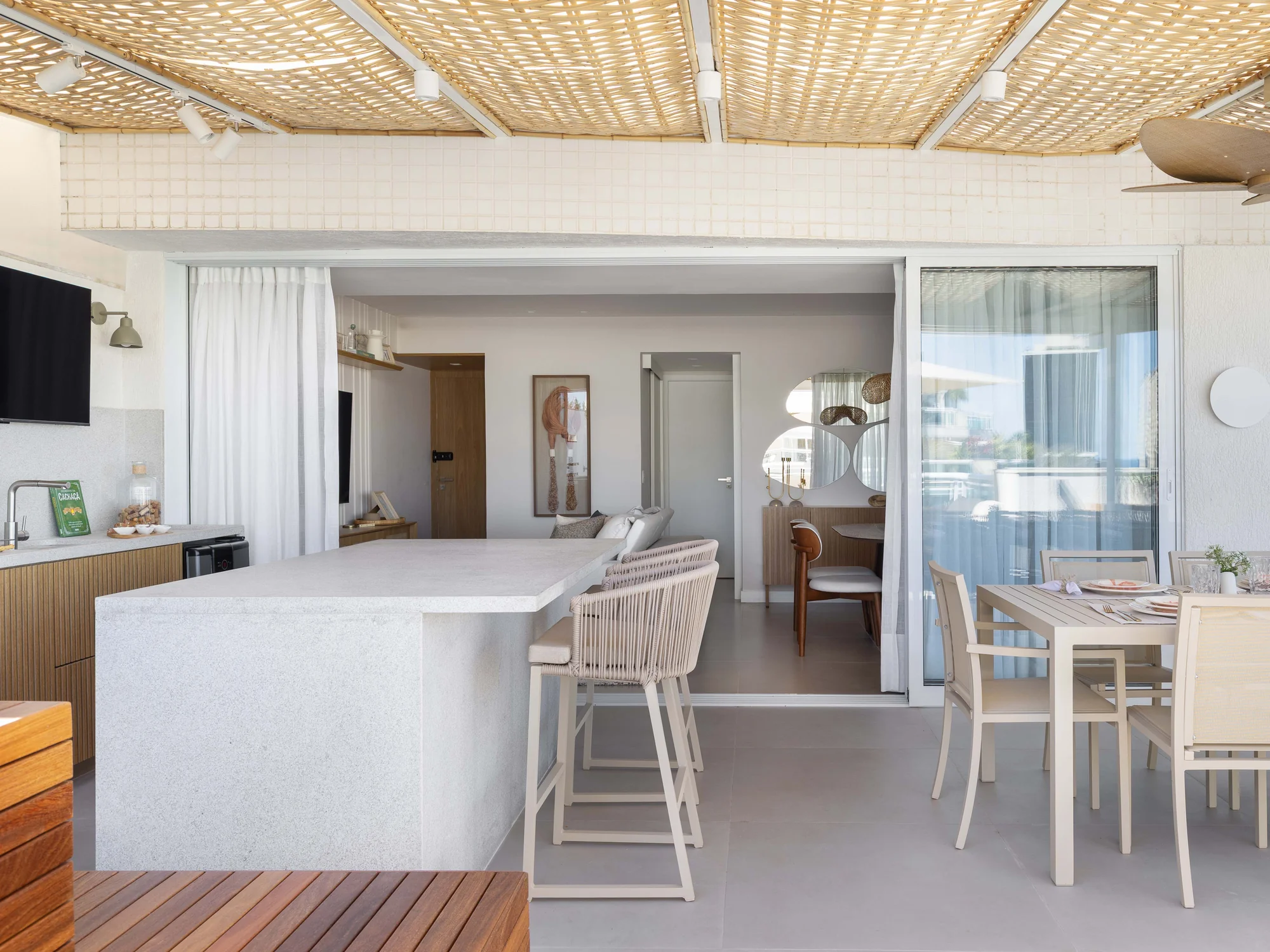 Vista do deck para o interior do apartamento, com ilha e sala de jantar