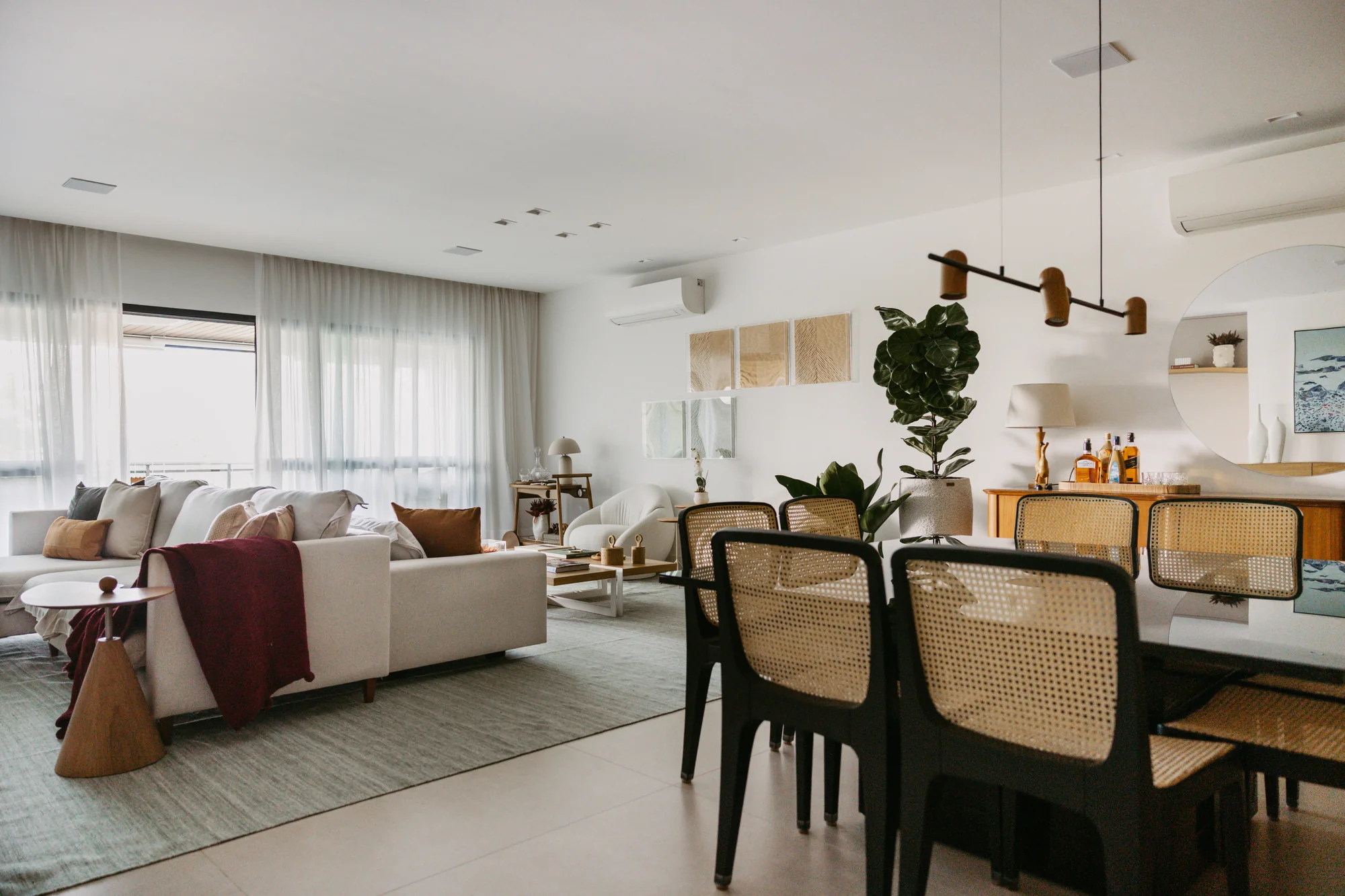 Living e sala de jantar integrados, com cadeiras de palhinha e pendente linear