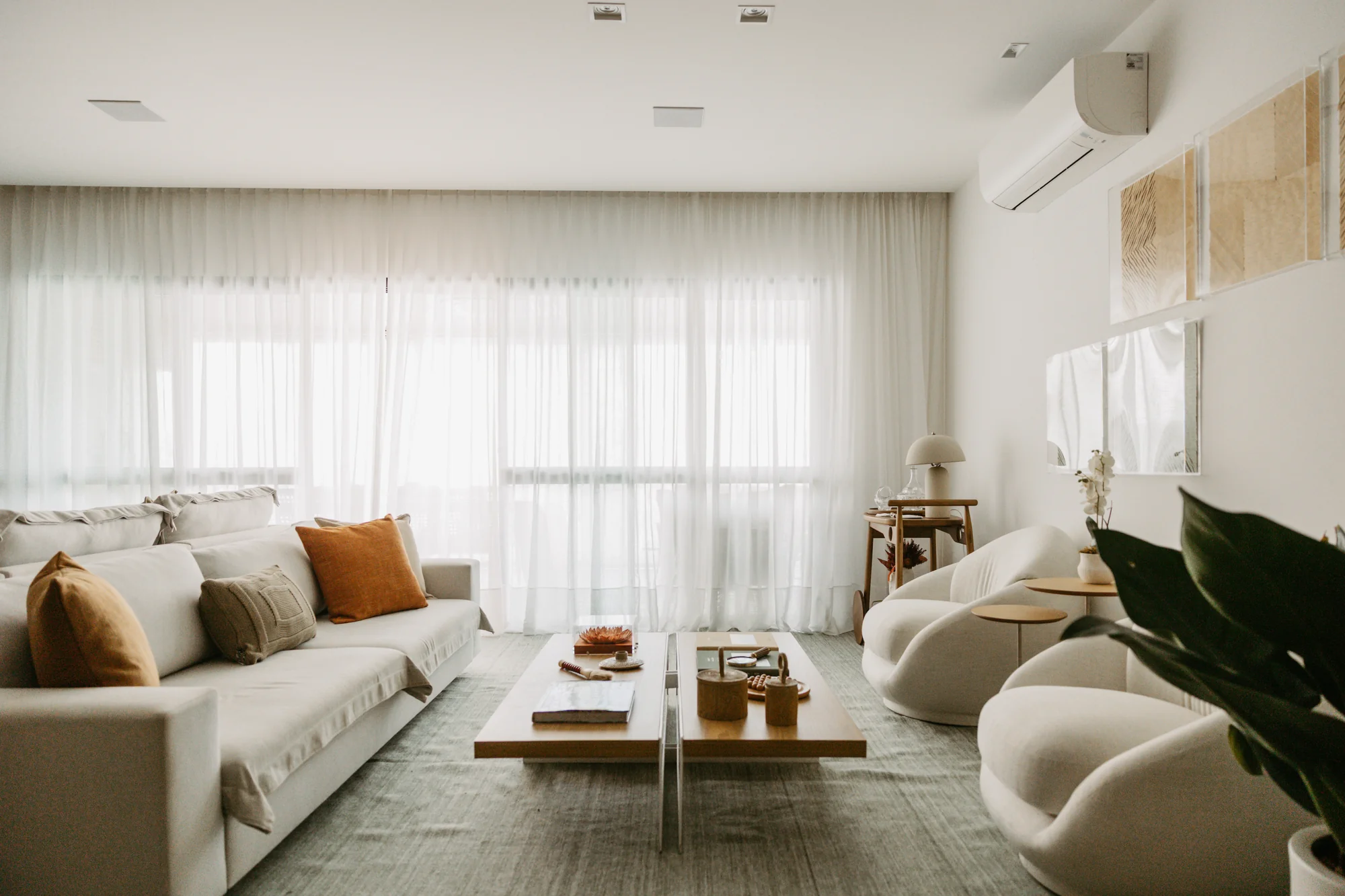 Sala de estar com sofá em L, mesa de centro baixa e poltronas curvas