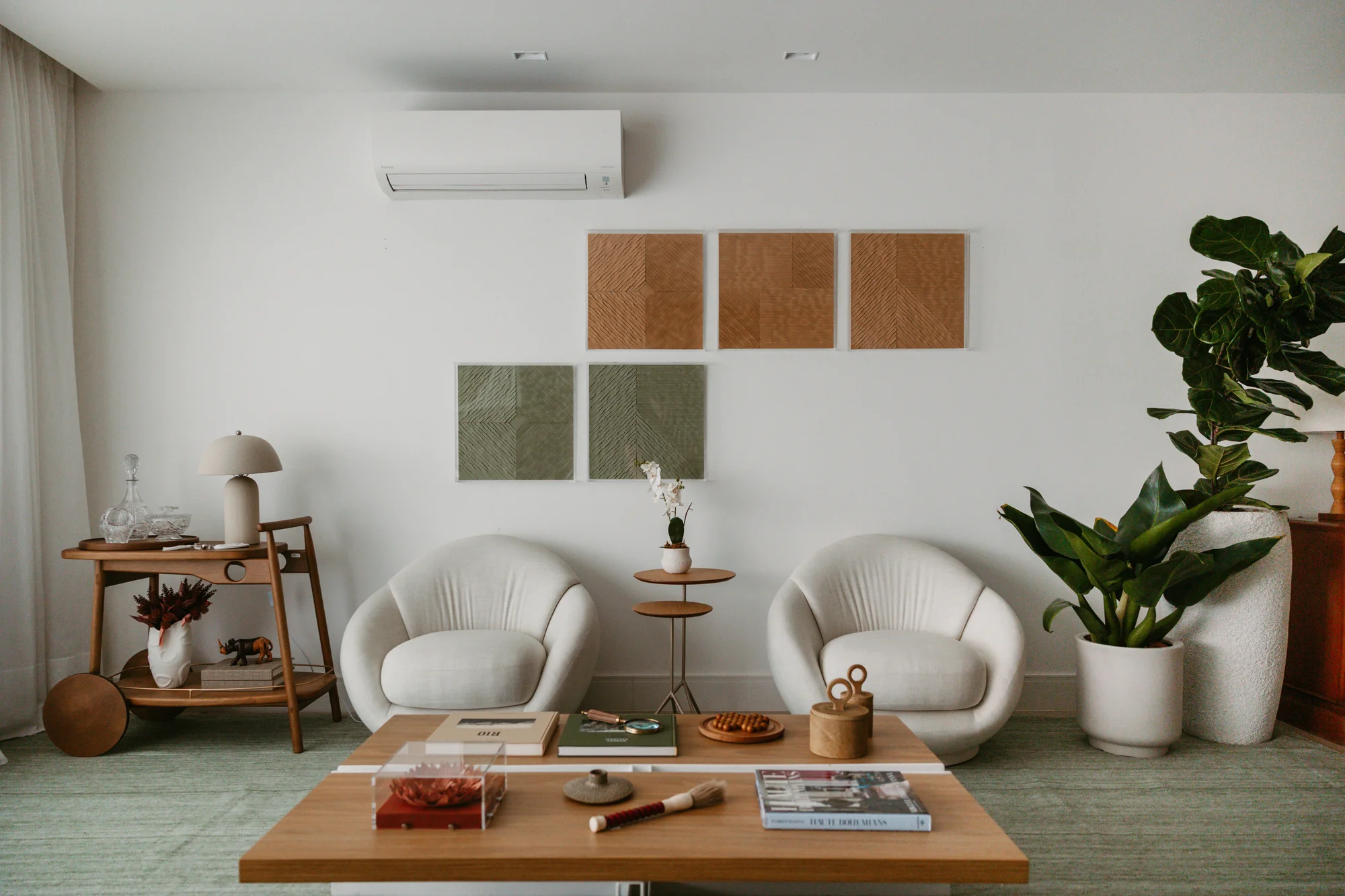 Poltronas curvas brancas diante do painel de quadros e da planta