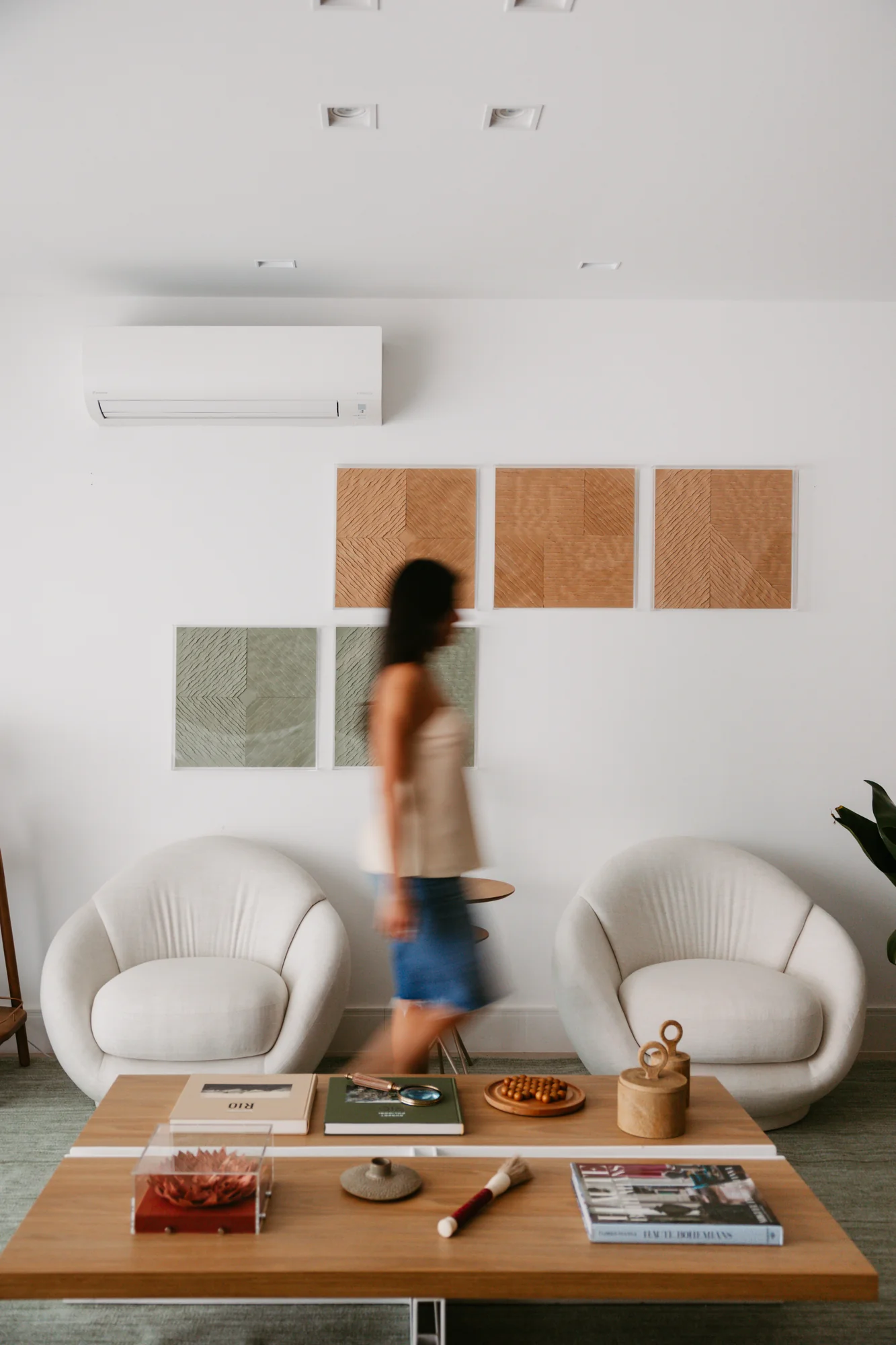 Moradora atravessa a sala entre as poltronas e a mesa de centro