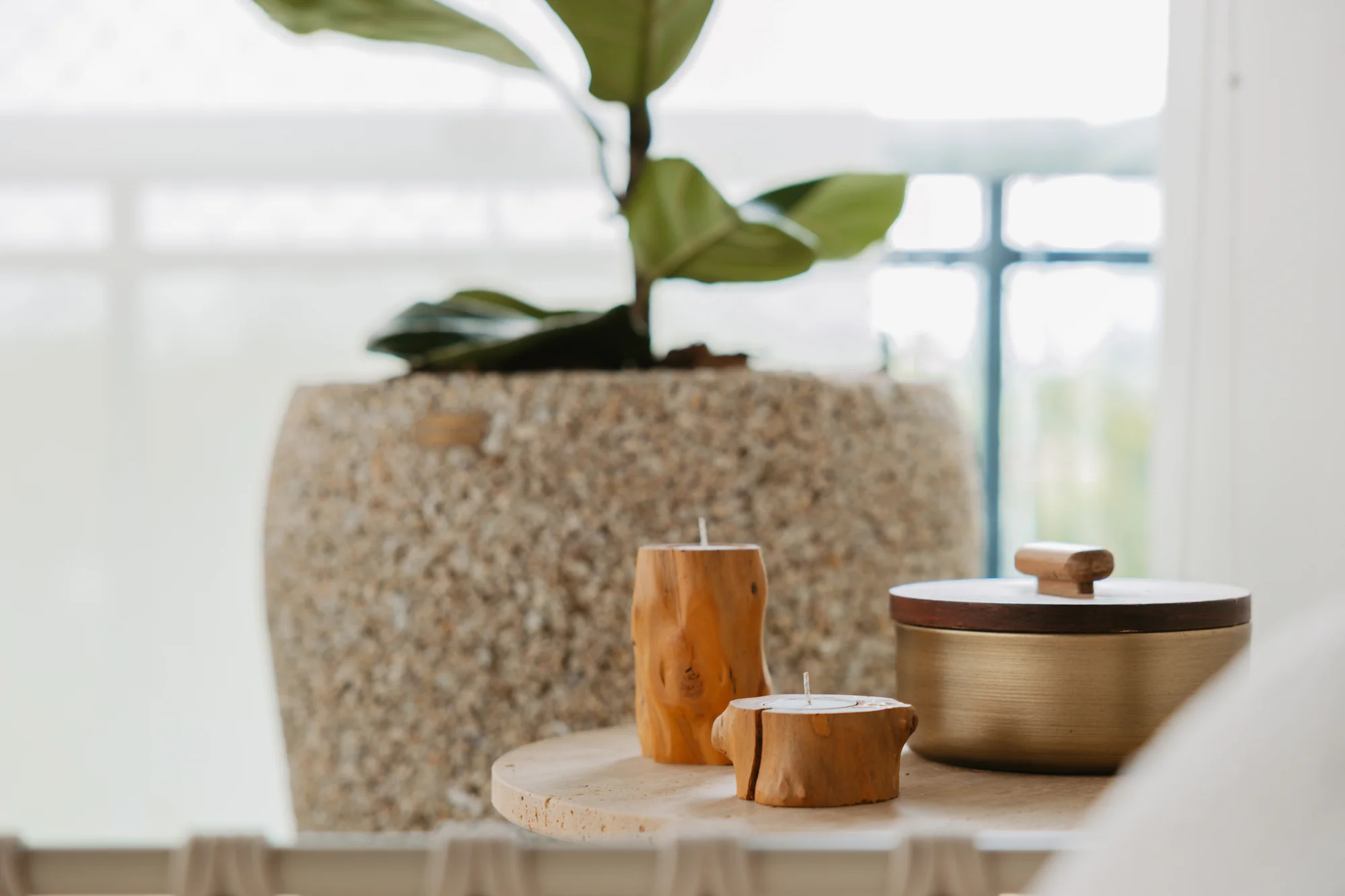 Detalhe de vaso texturizado e potes de madeira sobre a mesa de centro