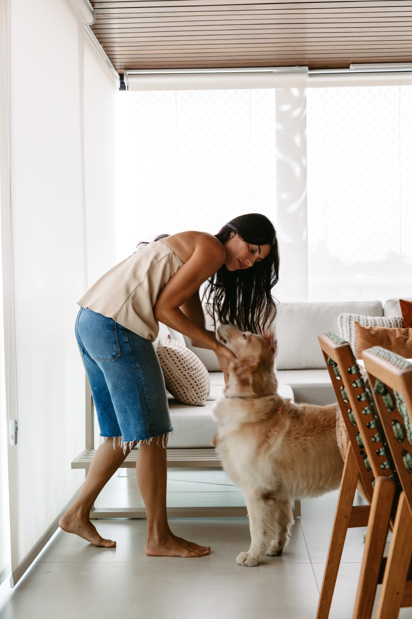 Moradora brinca com o cachorro na sala de jantar
