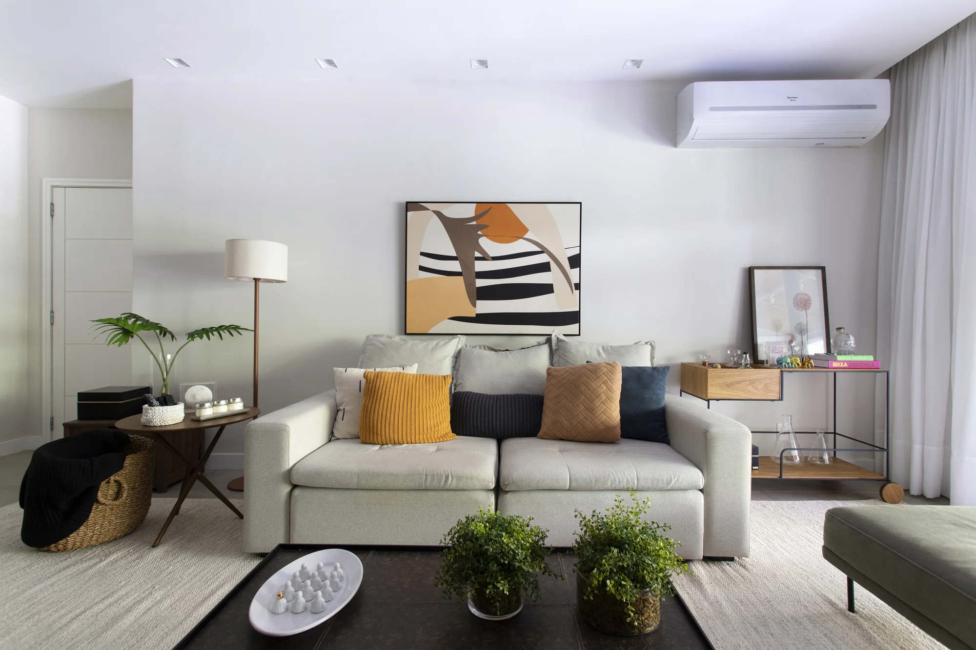 Sofá claro com almofadas amarelas e quadro geométrico na parede