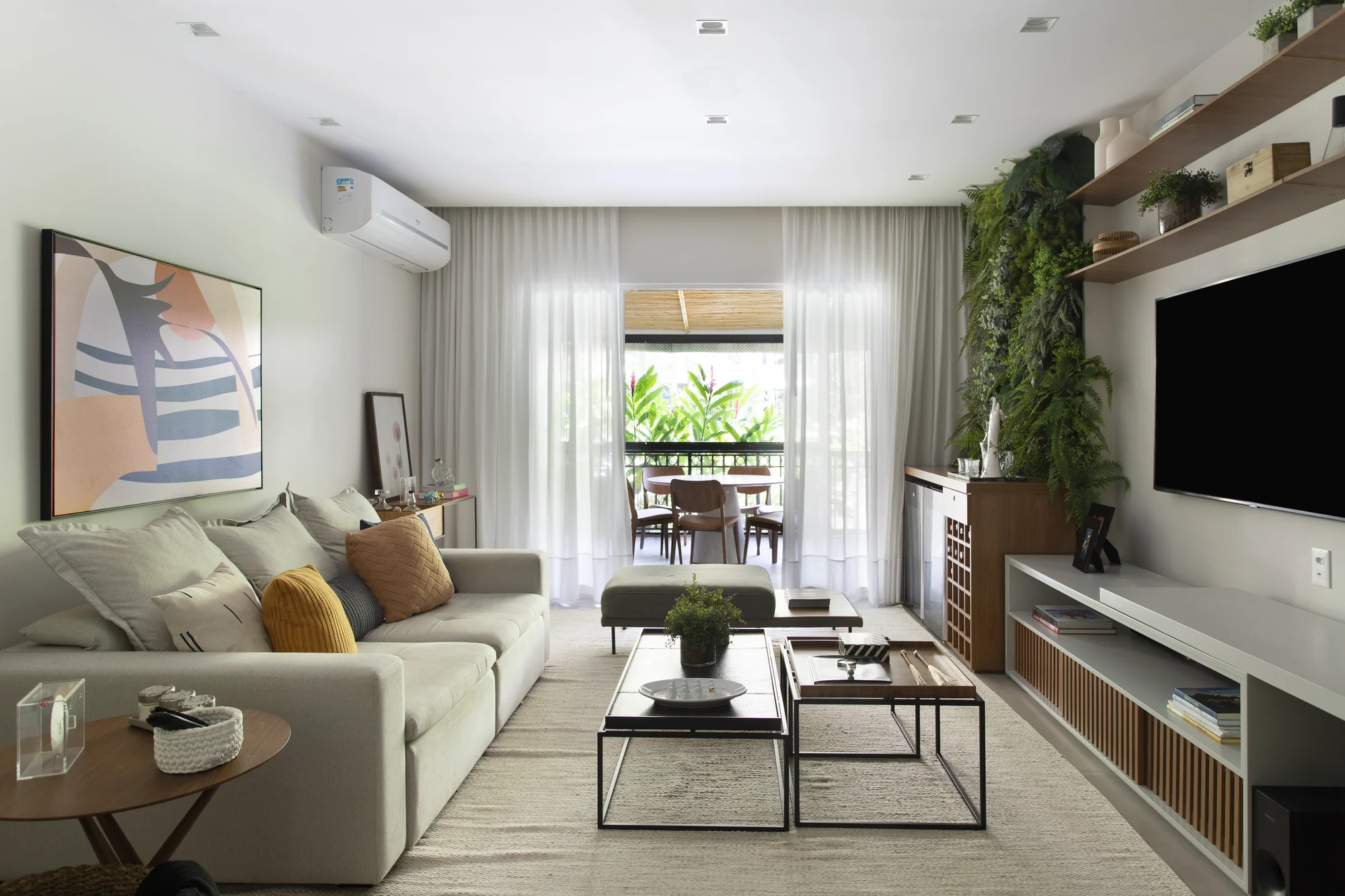 Living em enfiada, do sofá até o painel de televisão e o jardim vertical