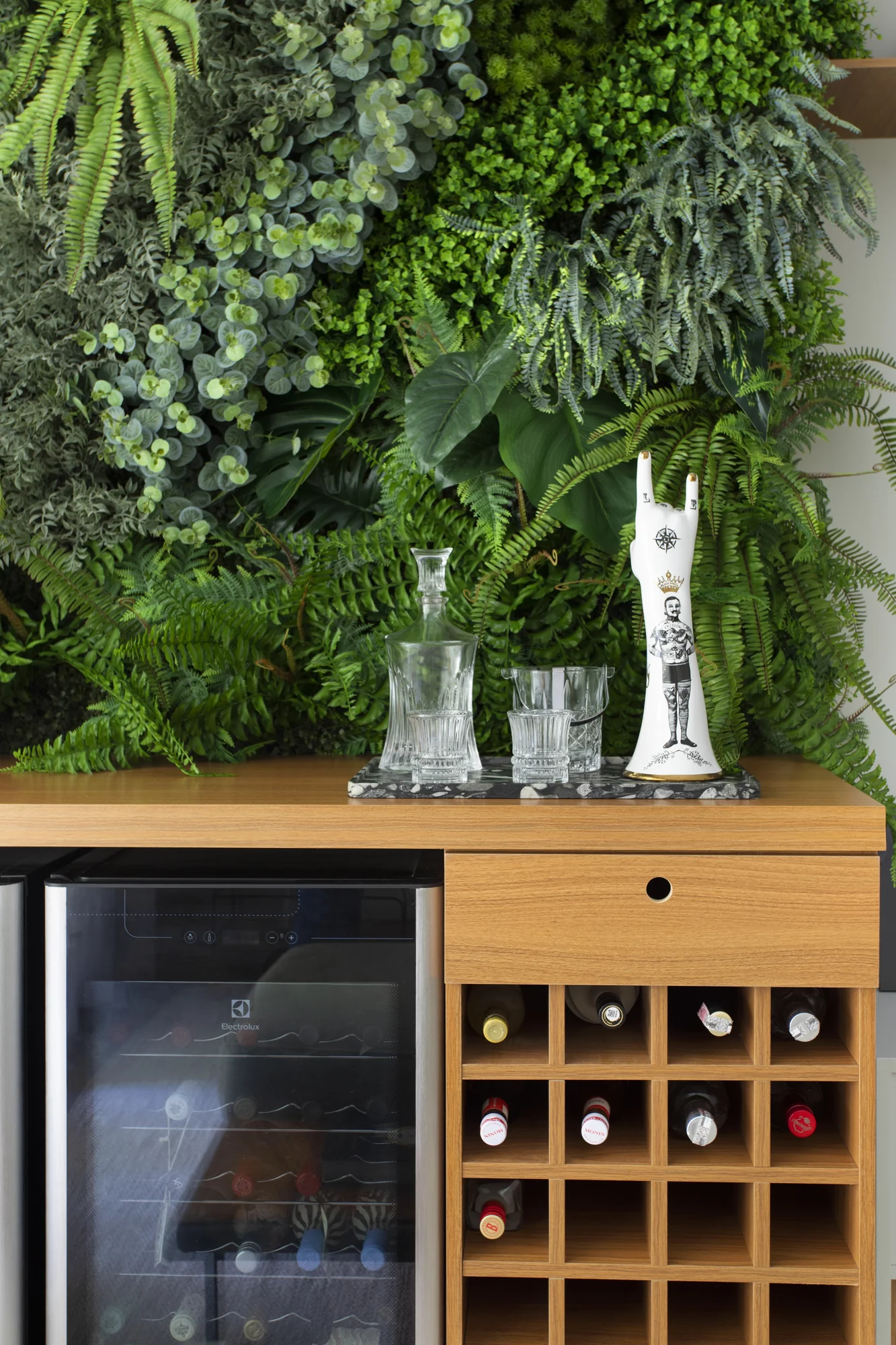 Detalhe do bar com jardim vertical, taças e adega de garrafas