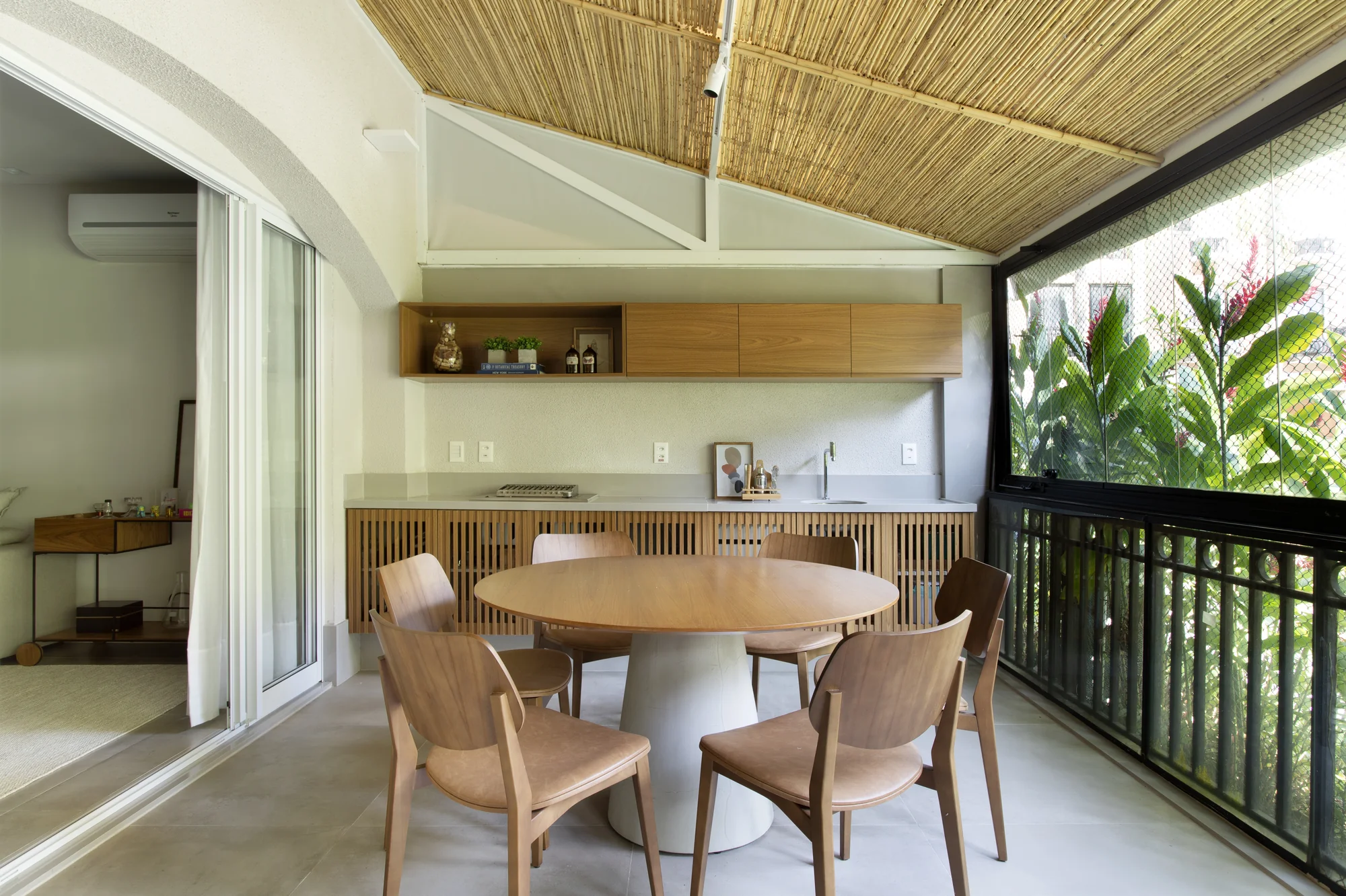 Varanda com mesa de refeições, bancada de madeira e guarda-corpo escuro